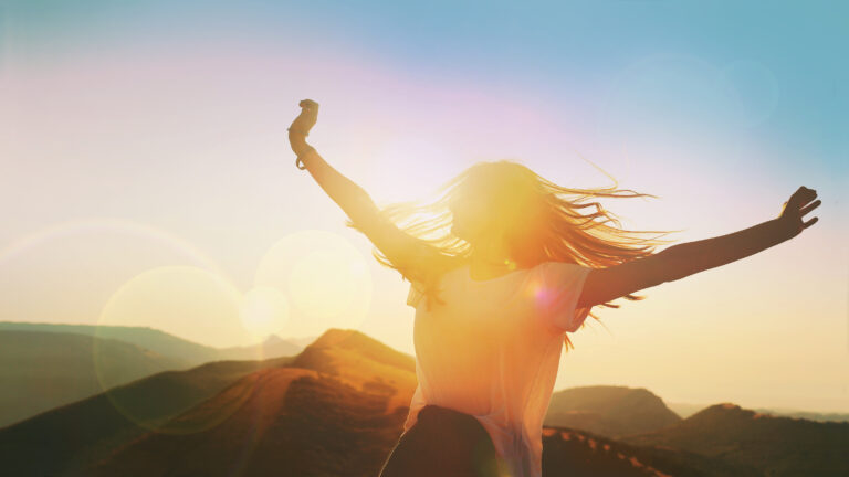 Girl on a background of mountains joyful spread her arms dancing